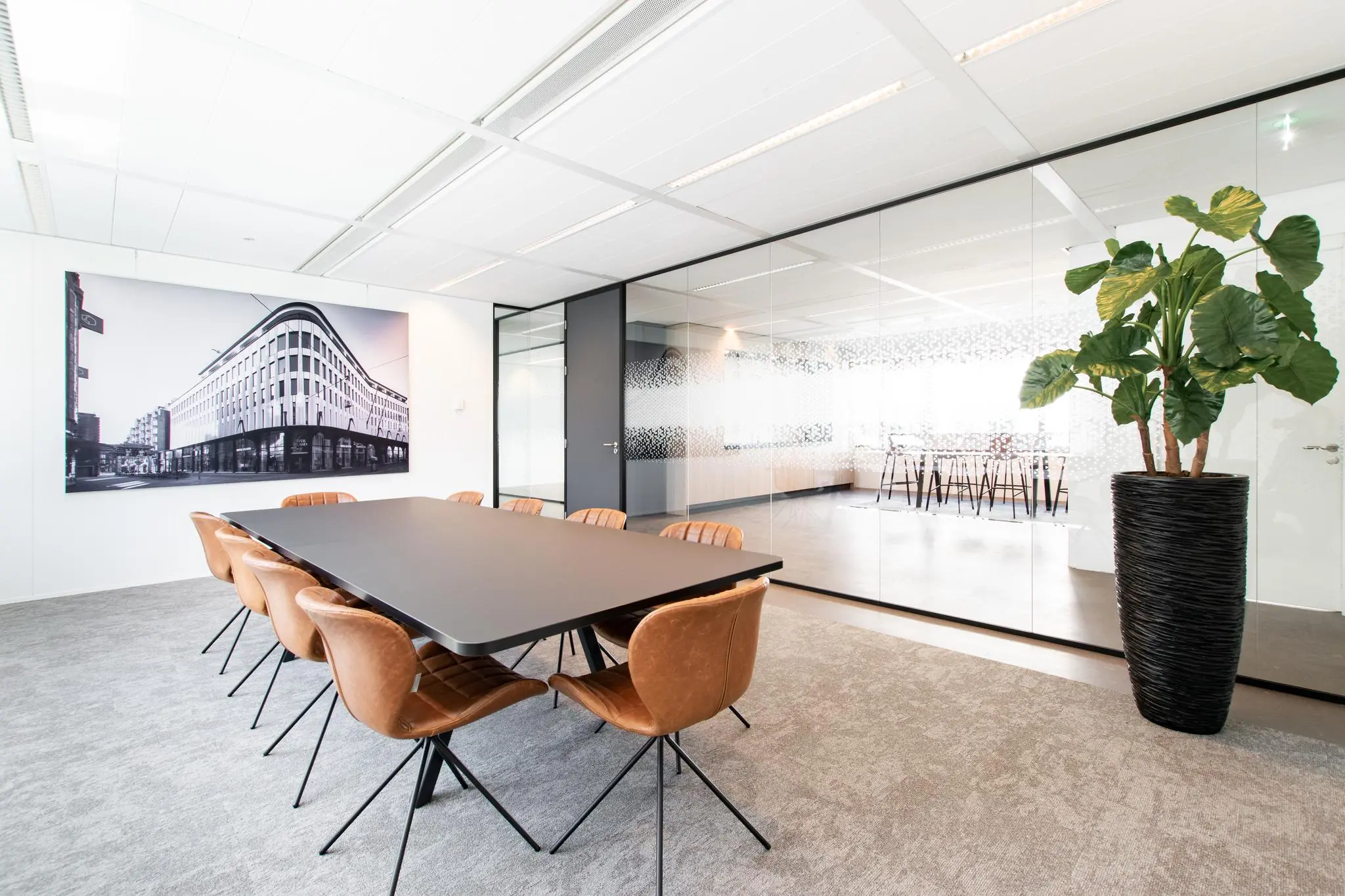 Vergaderruimte met moderne inrichting, lederen stoelen, glazen wand en een grote zwart-witfoto van de Grote Marktstraat aan de muur.